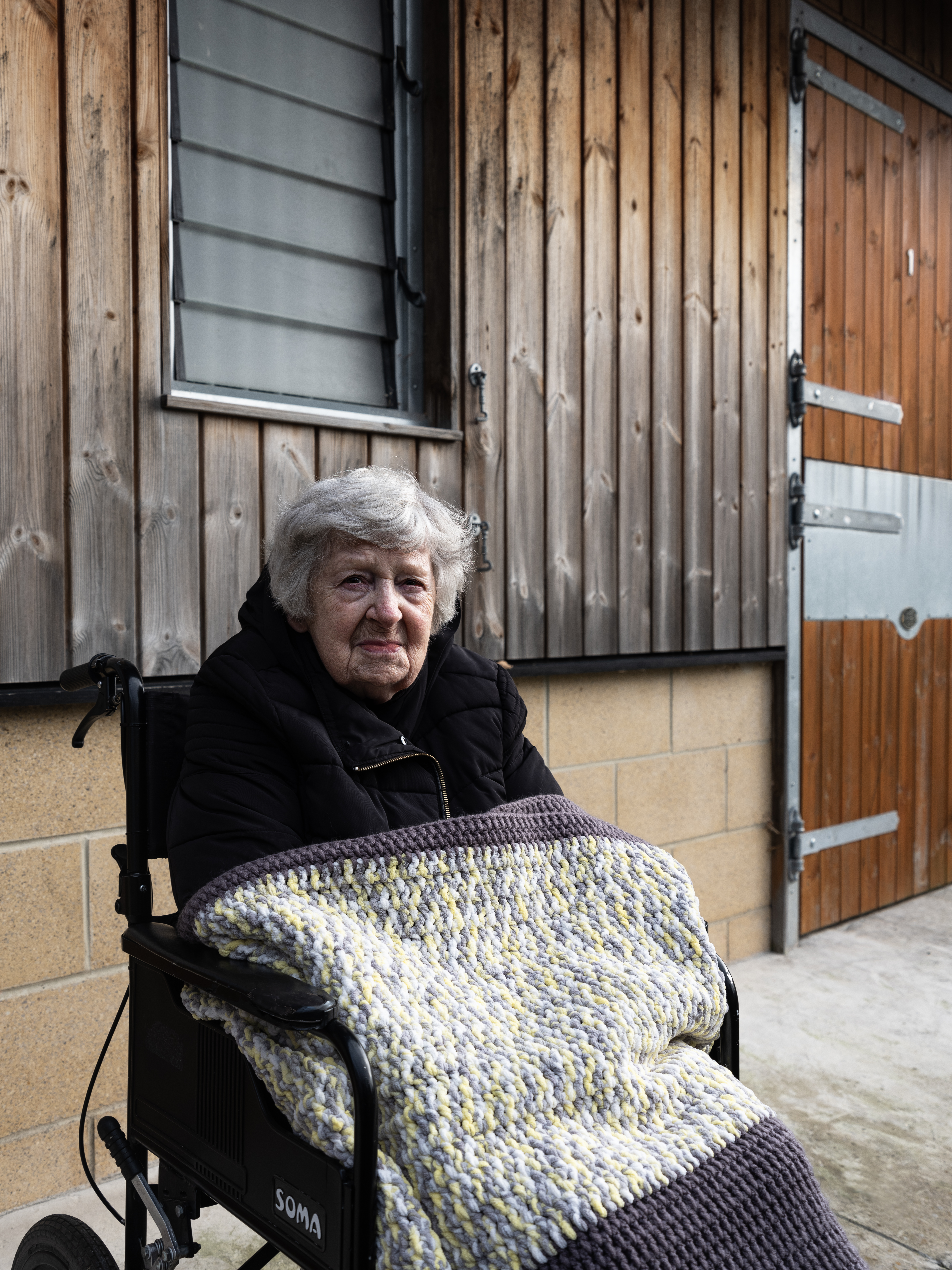 Rita she/her is an Irish white woman in her 70s. She is photographed at Cheltenham racecourse at the horse's stables which is her favourite place in Gloucestershire as it reminds her of her father who was a horse trainer and attended many Cheltenham Race Festivals.