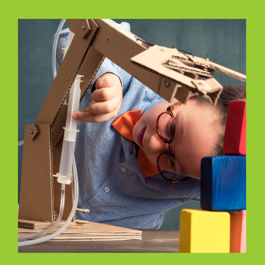 A photo of a boy constructing a robotic arm out of cardboard