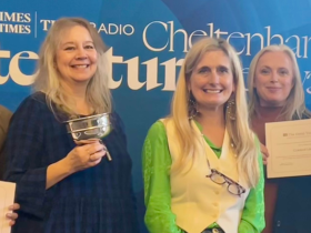 Four library staff lined up on either side of author Cressida Cowell, holding certificates and a trophy.