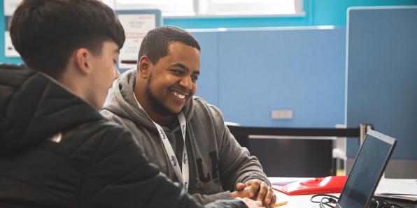 Two young men sat at a laptop