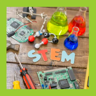 A photo of a workbench with tools, wires, flasks, motherboards, and the word 'STEM' laid out on the surface