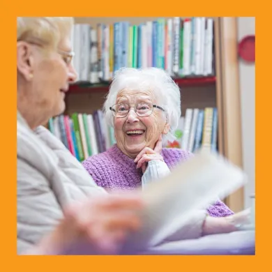 A photo of two women with grey hair laughing around a table