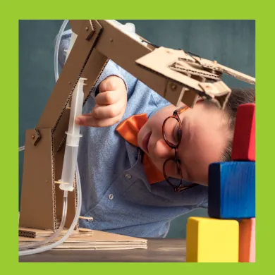 A photo of a boy constructing a robotic arm out of cardboard