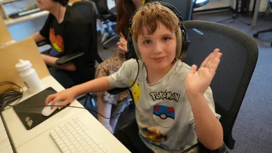 Young boy waving at the camera and wearing headphones
