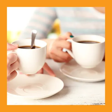 Photo of two different people's hands holding a mug of coffee
