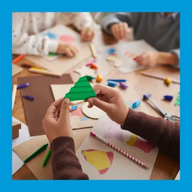 Children's hands holding green craft paper