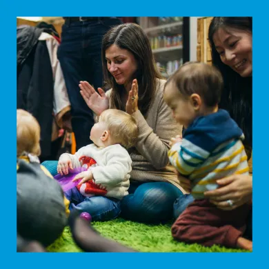 A lady clapping and smiling at a baby on her lap.