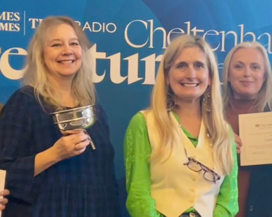 Four library staff lined up on either side of author Cressida Cowell, holding certificates and a trophy.